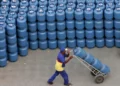 Homem transportando botijões de gás, representando a distribuição de gás para o Auxílio Gás.