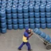 Homem transportando botijões de gás, representando a distribuição de gás para o Auxílio Gás.