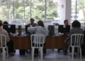 Pessoas participando de atendimento em um espaço público com computadores.