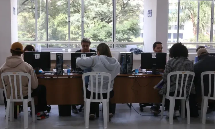 Pessoas participando de atendimento em um espaço público com computadores.