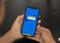 Imagem de uma pessoa segurando um celular com o aplicativo CadÚnico 2025 na tela, destacando a inscrição para o Cadastro Único.