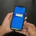 Imagem de uma pessoa segurando um celular com o aplicativo CadÚnico 2025 na tela, destacando a inscrição para o Cadastro Único.