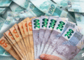 Dinheiro em cédulas brasileiras com destaque para valores de R$50 e R$200, representando a liberação de valores pelo governo.