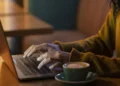 Pessoa utilizando notebook com uma xícara de café ao lado, simbolizando o acesso digital ao app da Receita Federal