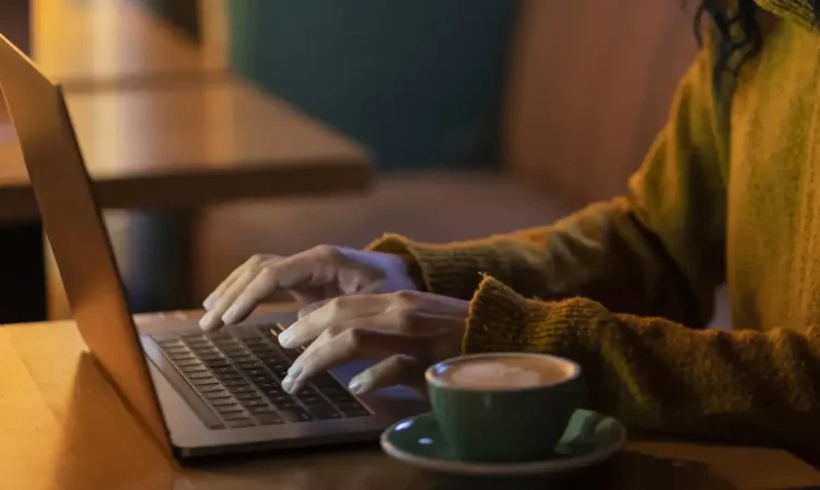 Pessoa utilizando notebook com uma xícara de café ao lado, simbolizando o acesso digital ao app da Receita Federal