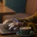 Pessoa utilizando notebook com uma xícara de café ao lado, simbolizando o acesso digital ao app da Receita Federal