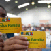 Cartões do programa Bolsa Família sendo exibidos por beneficiários em um evento de entrega.