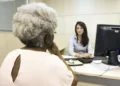 Beneficiária conversa com atendente em agência para resolver pendências de valores do INSS.