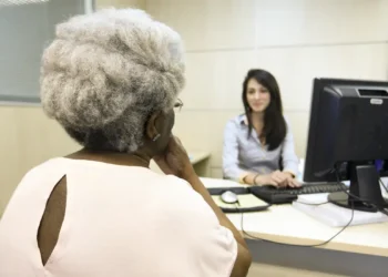 Beneficiária conversa com atendente em agência para resolver pendências de valores do INSS.