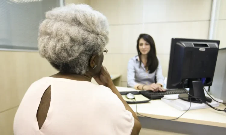 Beneficiária conversa com atendente em agência para resolver pendências de valores do INSS.