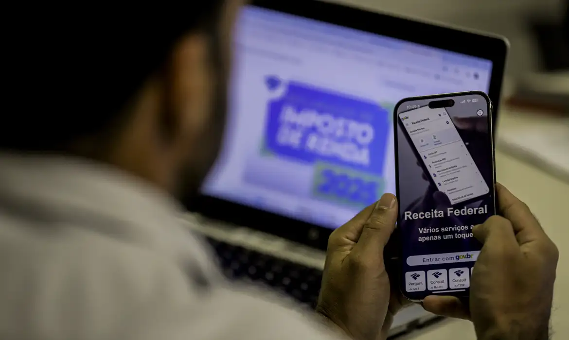 Pessoa utilizando o aplicativo da Receita Federal no celular para acessar serviços relacionados ao Imposto de Renda.