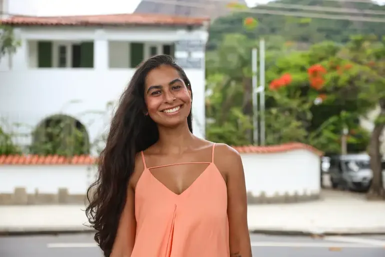 "Mulher sorrindo, ilustrando o conceito de pessoas que moram sozinhas e podem se cadastrar no programa social."
