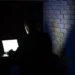 Pessoa usando notebook no escuro representa golpe digital aplicado por criminosos se passando pela Receita Federal