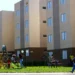 "Residencial do programa Minha Casa, Minha Vida com crianças brincando e morador caminhando, representando as condições diferenciadas de financiamento."