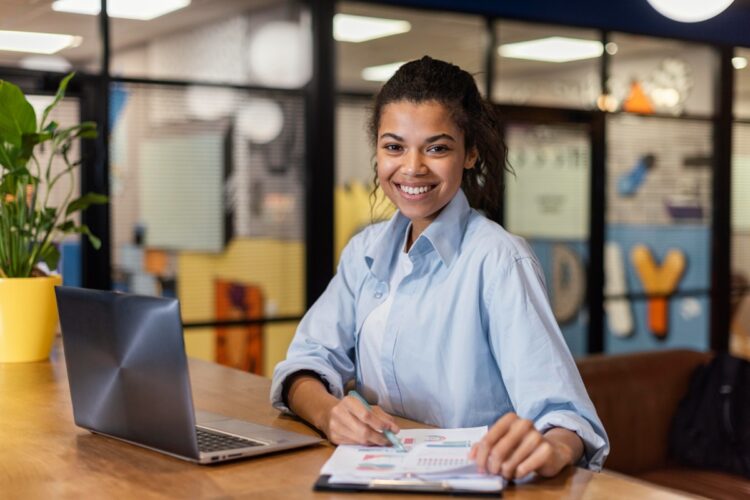 Mulher jovem com laptop e documentos em espaço de trabalho vibrante