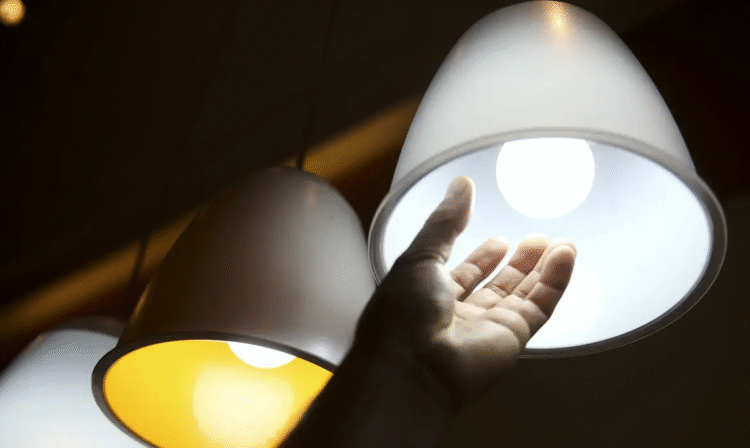 Pessoa tocando em uma lâmpada acesa, simbolizando o acesso à Tarifa Social de Energia e os benefícios de desconto na conta de luz.