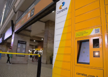 Terminal de autoatendimento dos Correios em estação movimentada.