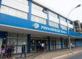 Fachada de agência da Previdência Social com pessoas entrando e saindo.