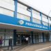 Fachada de agência da Previdência Social com pessoas entrando e saindo.
