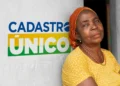 Mulher ao lado de mural com logo do Cadastro Único, representando a atualização cadastral em 2025.