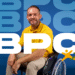 homem cadeirante sorrindo em frente ao fundo azul com a sigla BPC