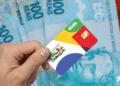 Cartão do Bolsa Família e cédulas de 100 reais, destacando a importância do programa para o auxílio financeiro em 2025.