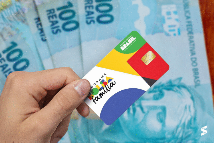 Cartão do Bolsa Família e cédulas de 100 reais, destacando a importância do programa para o auxílio financeiro em 2025.