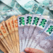Notas de dinheiro brasileiras nas cores laranja e cinza representando valores de 50 e 200 reais, simbolizando o pagamento do PIS/PASEP em andamento.