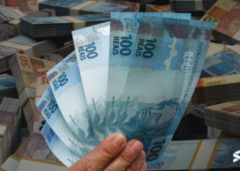 Cédulas de 100 reais destacadas ao fundo de notas de dinheiro, ilustrando o impacto financeiro do Auxílio Gás no Bolsa Família