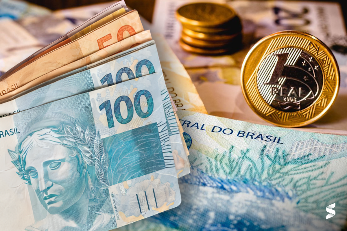 Cédulas de dinheiro e moedas ilustrando a relação do Imposto de Renda com o salário mínimo