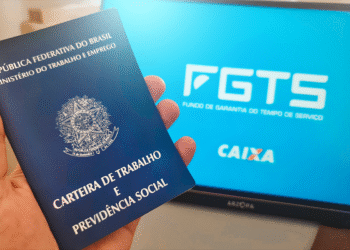 Carteira de Trabalho sendo segurada com tela do FGTS ao fundo, representando a manutenção das regras do saque-aniversário.