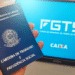Carteira de Trabalho sendo segurada com tela do FGTS ao fundo, representando a manutenção das regras do saque-aniversário.