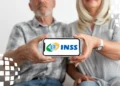 Casal idoso mostrando smartphone com logo do INSS, representando o calendário de pagamento da segunda parcela do 13º do INSS.