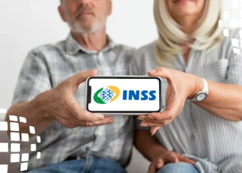 Casal idoso mostrando smartphone com logo do INSS, representando o calendário de pagamento da segunda parcela do 13º do INSS.