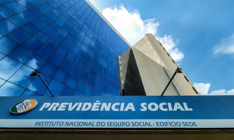 Fachada do Instituto Nacional do Seguro Social com céu azul refletido no prédio de vidro
