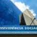 Fachada do Instituto Nacional do Seguro Social com céu azul refletido no prédio de vidro