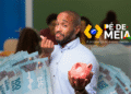 Homem sorrindo com dinheiro em mãos e cofrinho rosa, simbolizando o programa Pé-de-Meia e o incentivo financeiro para estudantes.
