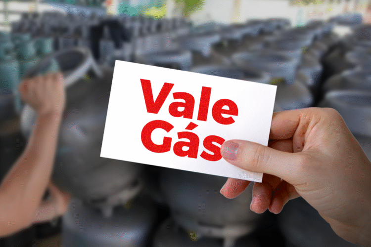 Cartão do Vale Gás sendo segurado por uma mão em frente a botijões de gás