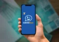 Mão segurando celular com aplicativo Caixa Tem aberto na tela