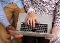 Pessoa idosa usando laptop com ajuda de outra pessoa para acompanhar pedido do Auxílio-doença online