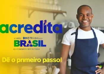 Homem sorrindo em uma cafeteria, com o logo 'acredita' e a mensagem de incentivo para dar o primeiro passo, do Governo Federal do Brasil.