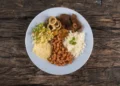 Prato tradicional brasileiro com arroz, feijão, carne, salada e farofa, representando alimentação acessível na comunidade.