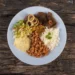 Prato tradicional brasileiro com arroz, feijão, carne, salada e farofa, representando alimentação acessível na comunidade.