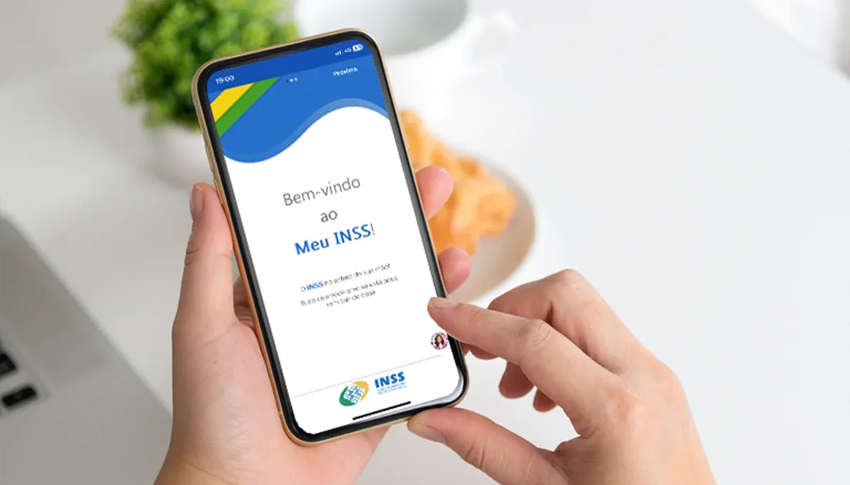 Pessoa usando um smartphone com a tela do aplicativo 'Meu INSS', verificando informações sobre aposentadoria.