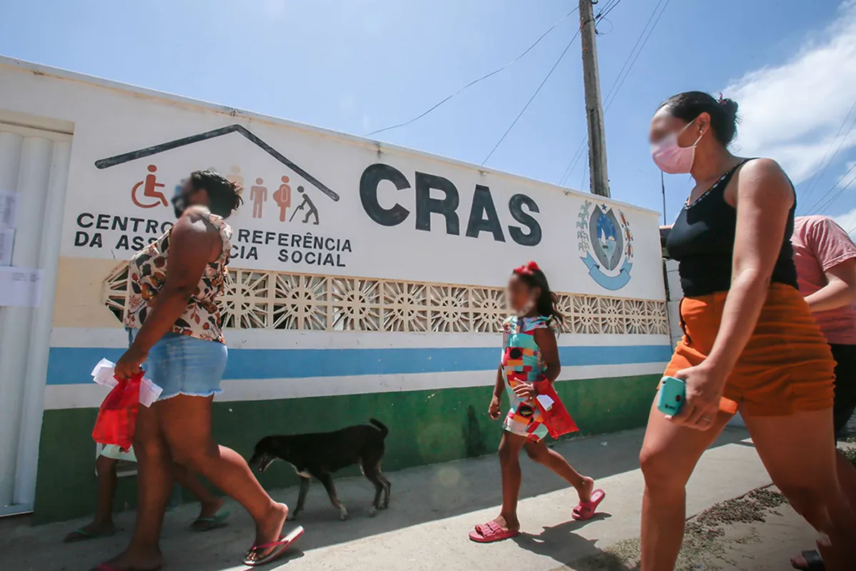Famílias caminhando em frente a uma unidade do CRAS em dia de atendimento social.