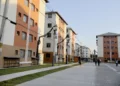 Prédios residenciais modernos com pessoas caminhando, ilustrando moradia urbana acessível.