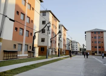 Prédios residenciais modernos com pessoas caminhando, ilustrando moradia urbana acessível.