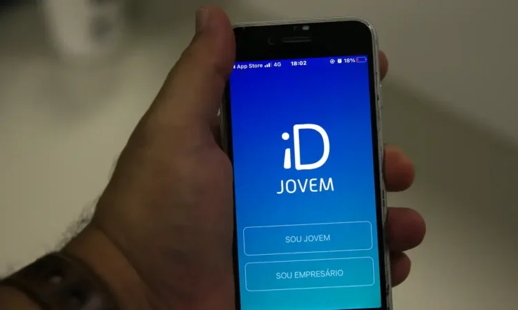 Mão segurando celular com o aplicativo ID Jovem aberto na tela