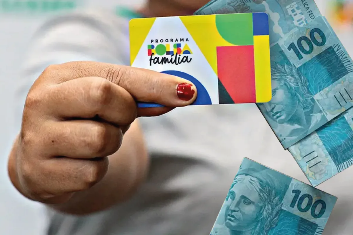 Pessoa segurando cartão do Bolsa Família com cédulas de dinheiro ao fundo.