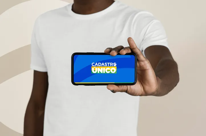 Pessoa segurando um celular com a tela exibindo o logo do CadÚnico 2025.